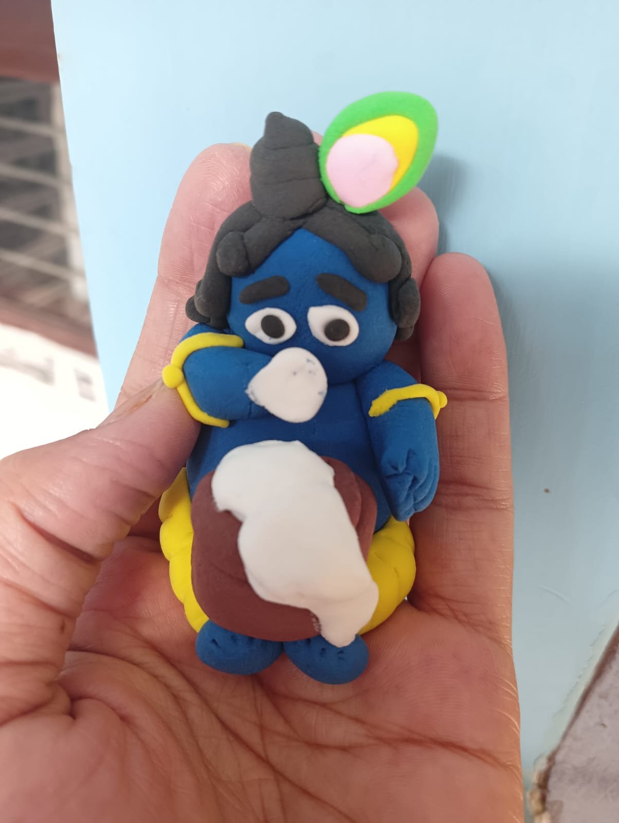 A tiny handmade clay figure resting in an open hand
