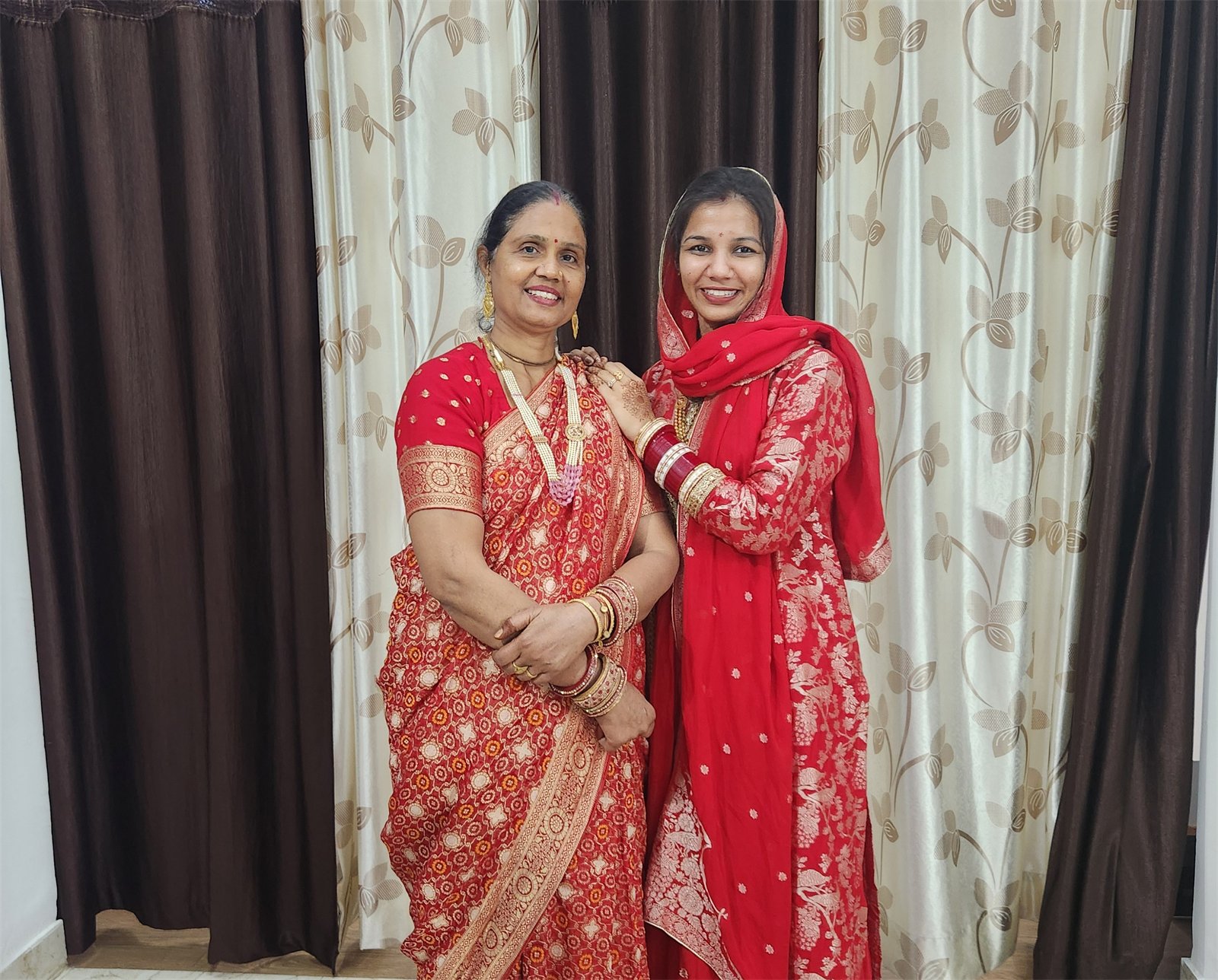 Two women smiling together in red traditional clothes