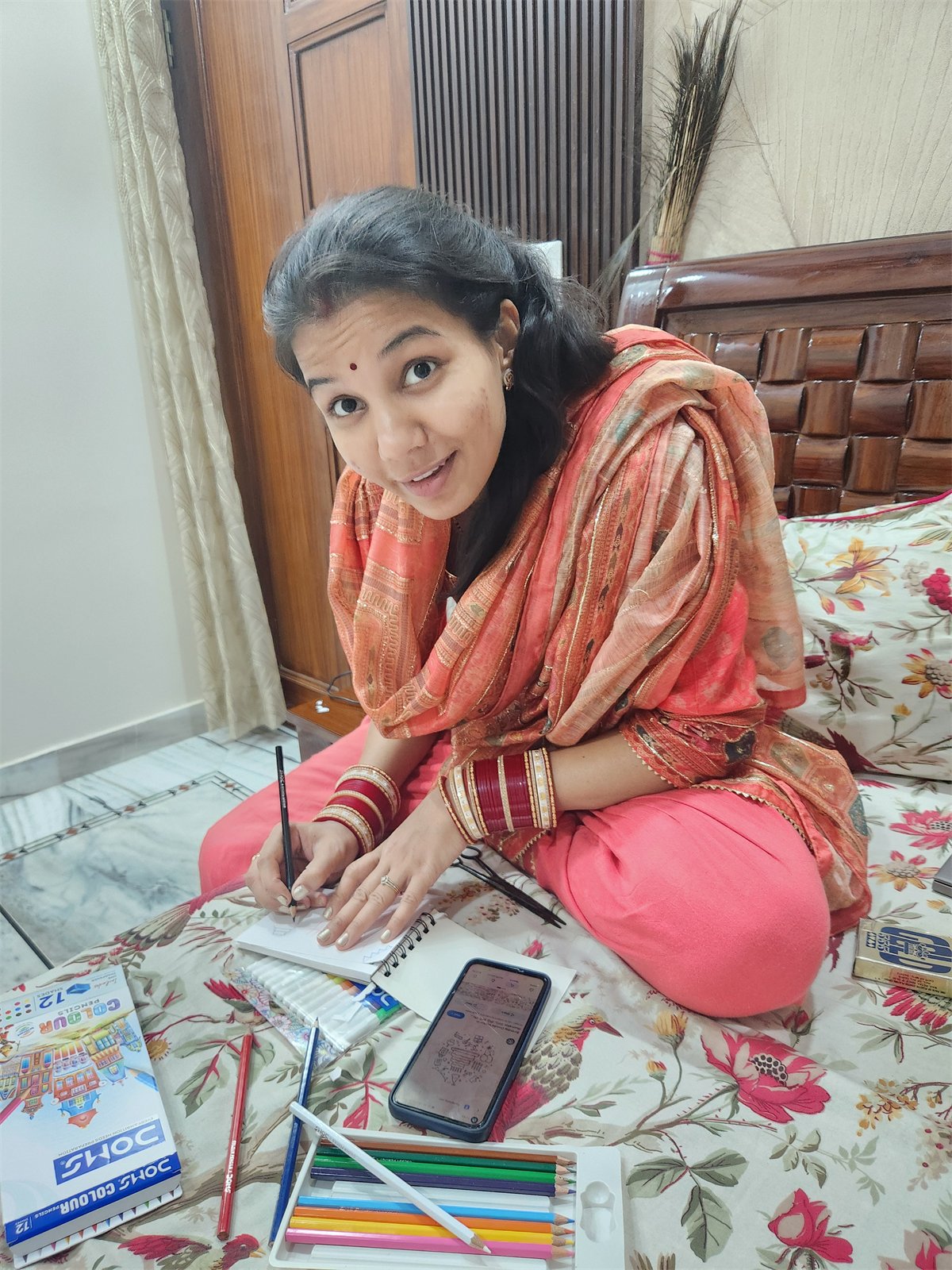A woman smiling while coloring on a bed