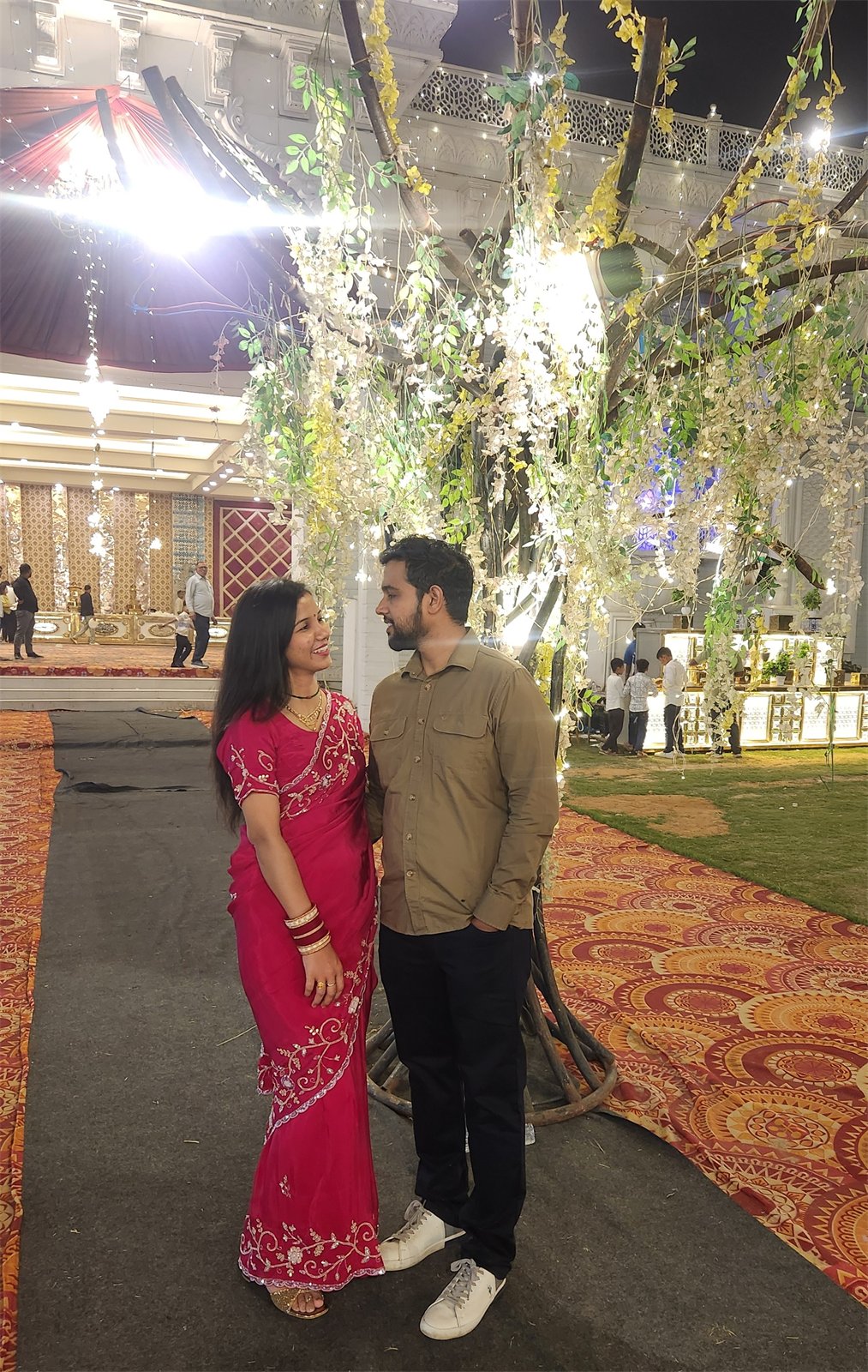 The two of us smiling at each other beneath celebration lights
