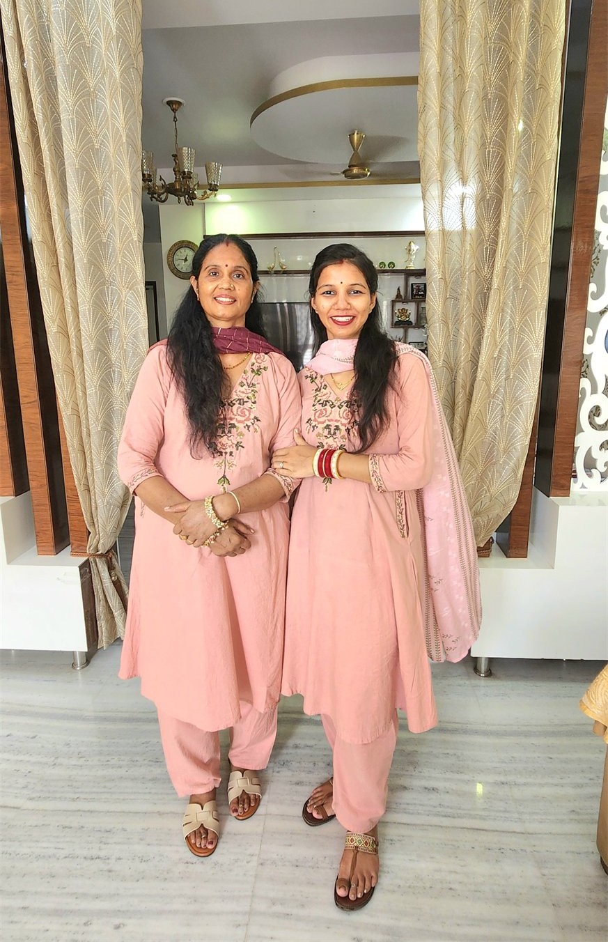 Two women standing together in matching pink outfits