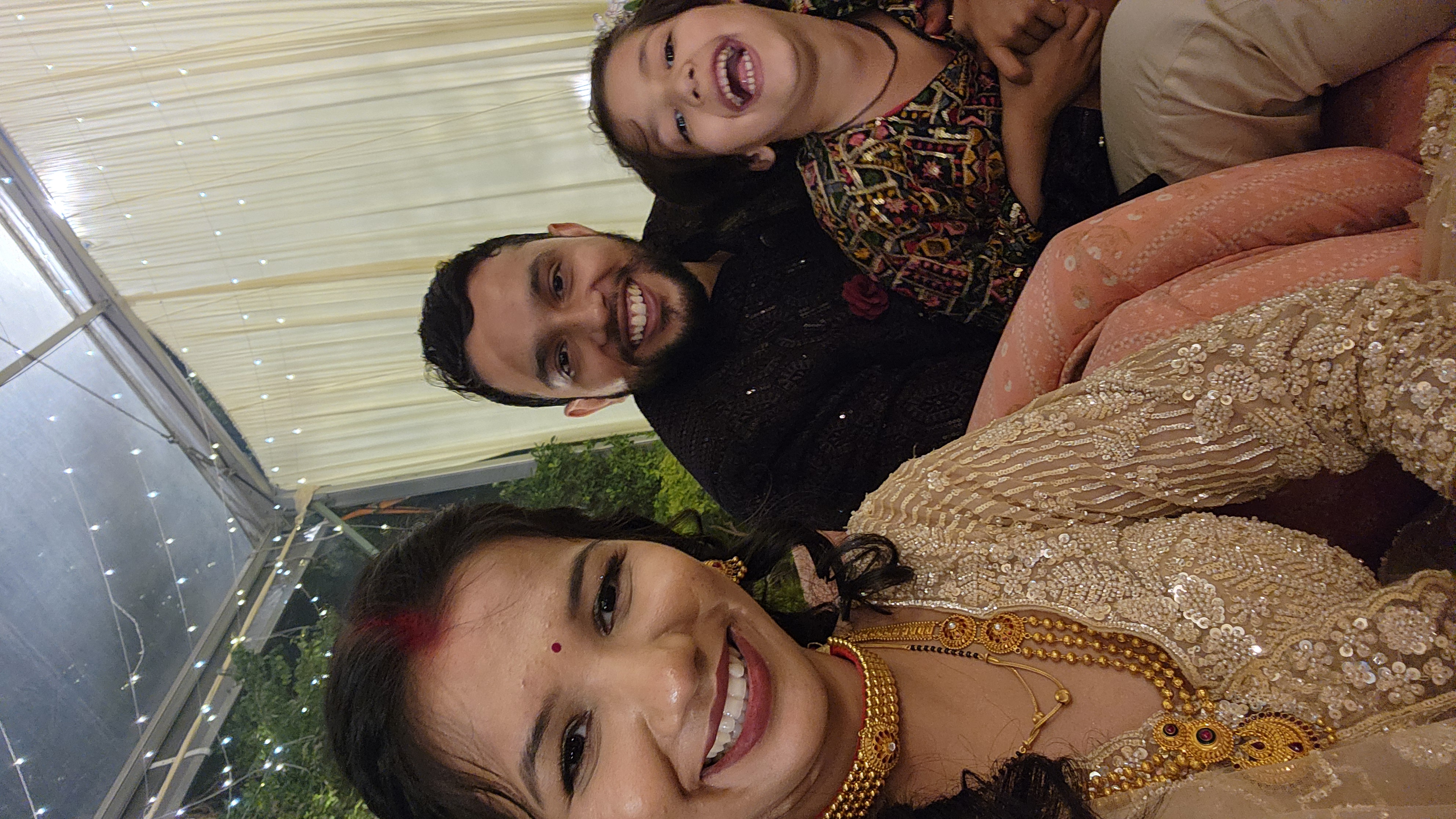 Three smiling people dressed for a celebration