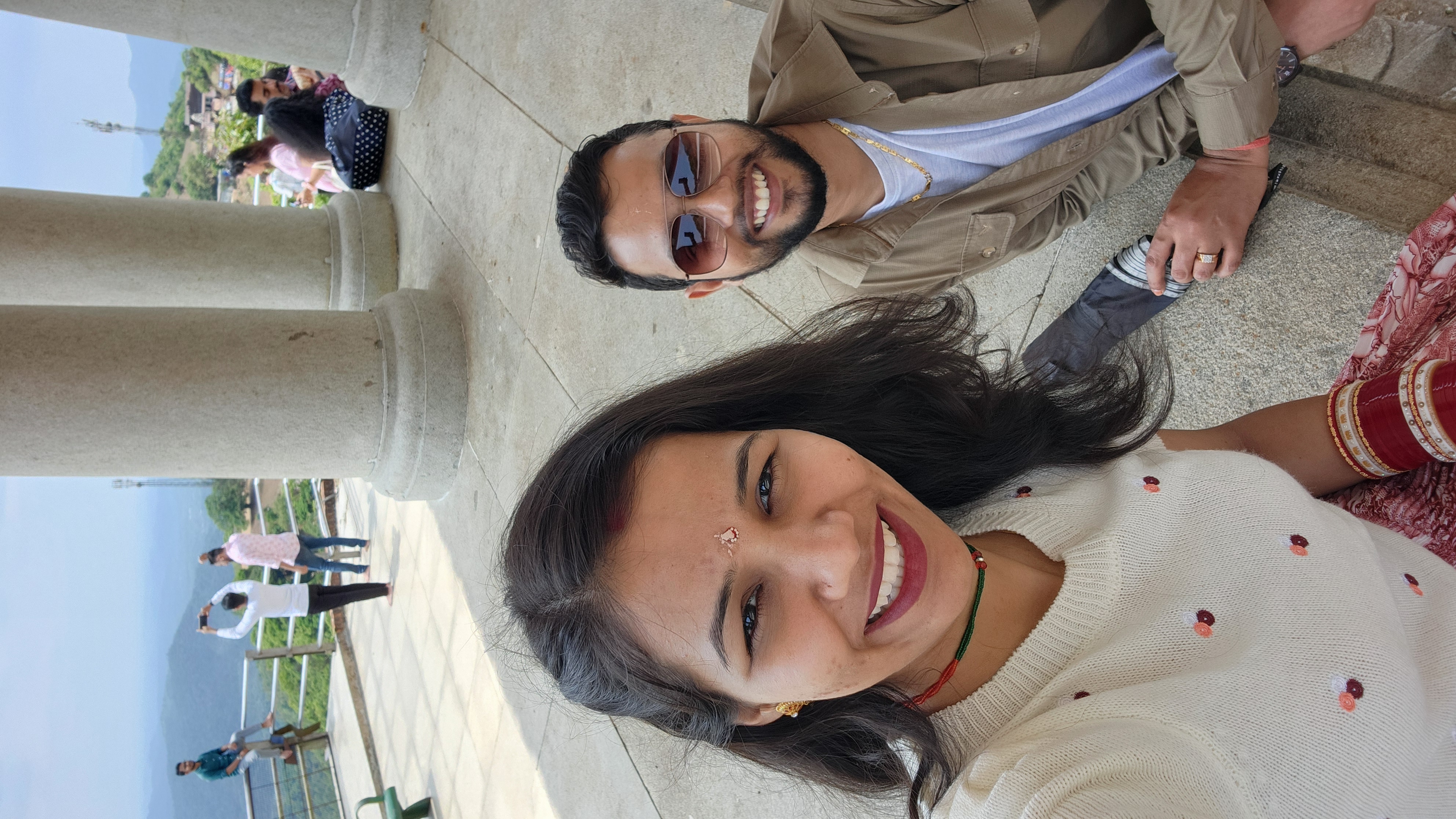 Couple taking an outdoor selfie beside stone columns