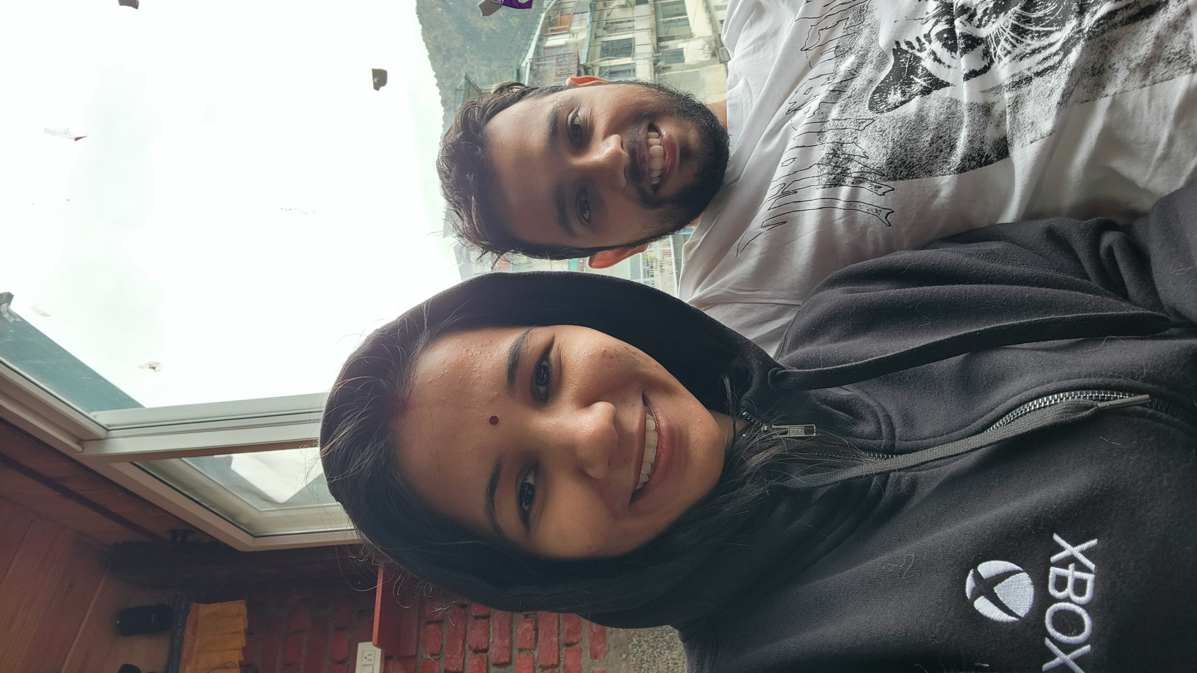 Couple smiling together in warm jackets by a window