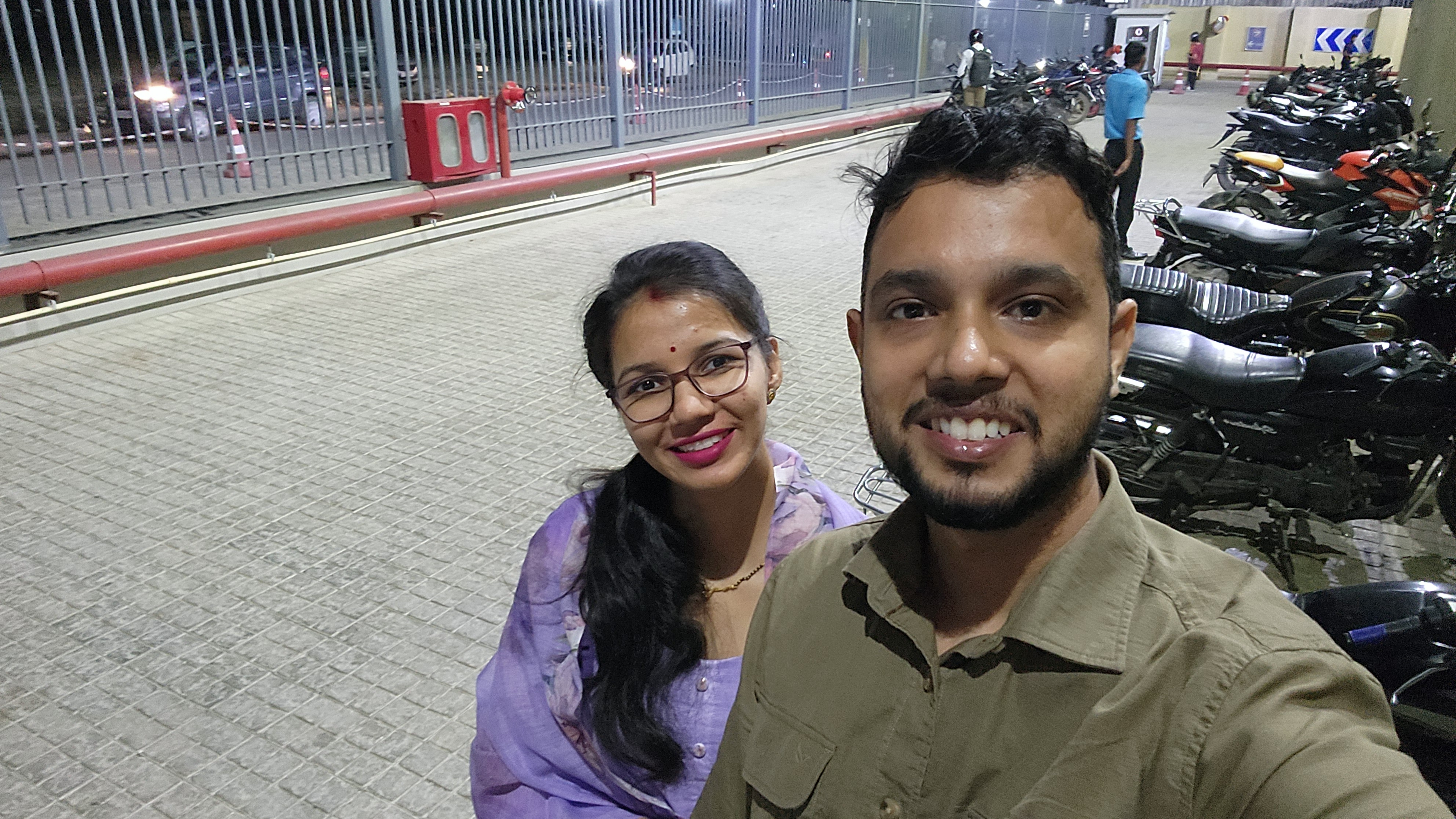Couple taking a nighttime selfie near parked motorcycles