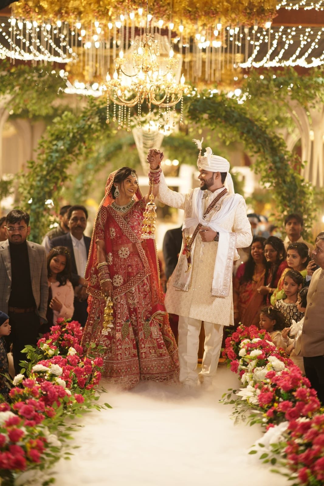 A bride and groom walking beneath wedding lights and flowers