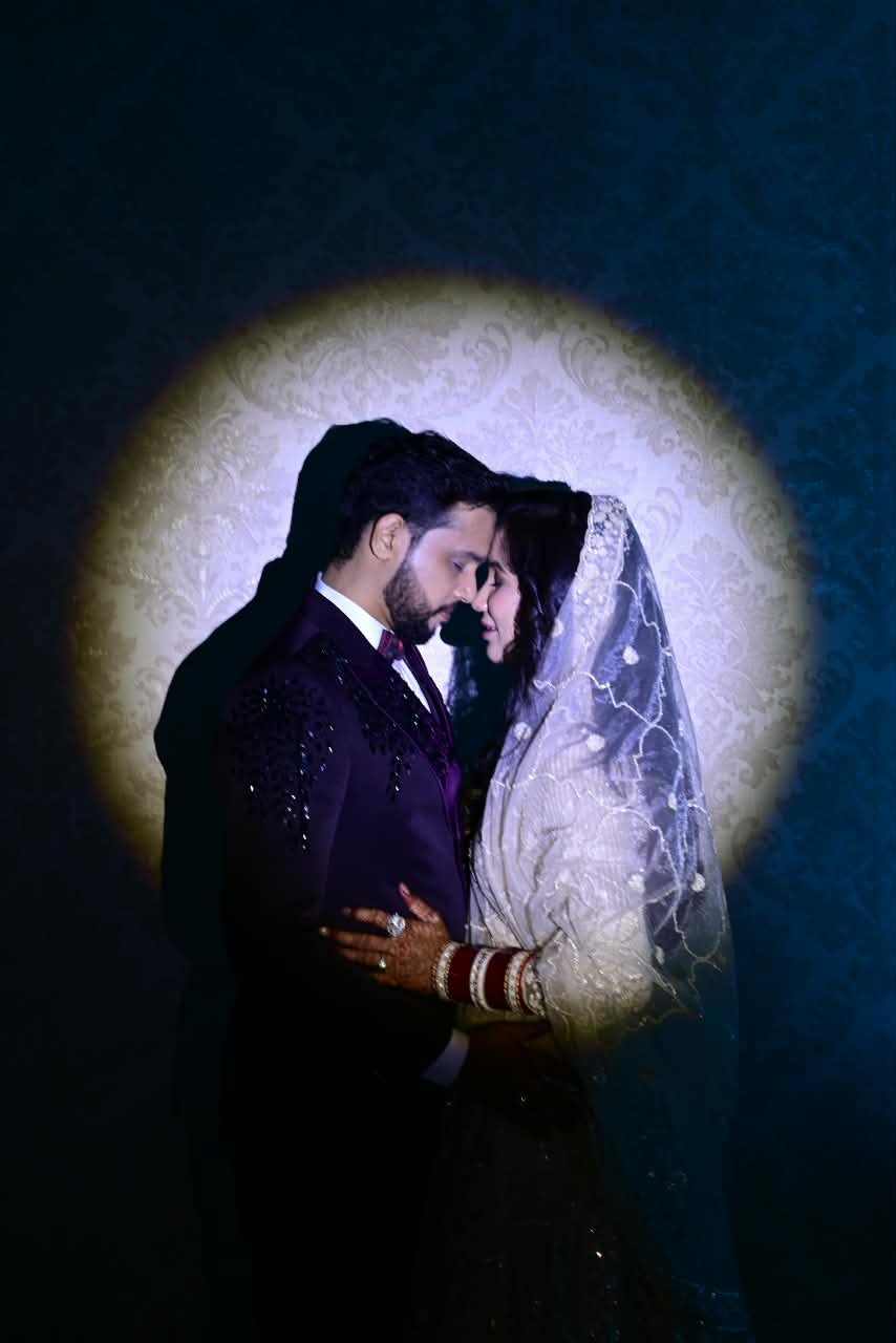 A bride and groom sharing a quiet embrace in a spotlight