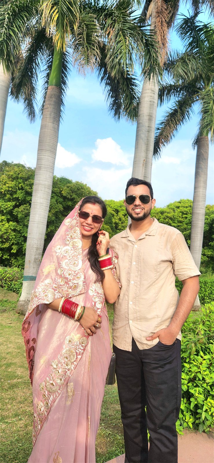 The two of us smiling side by side beneath tall palm trees