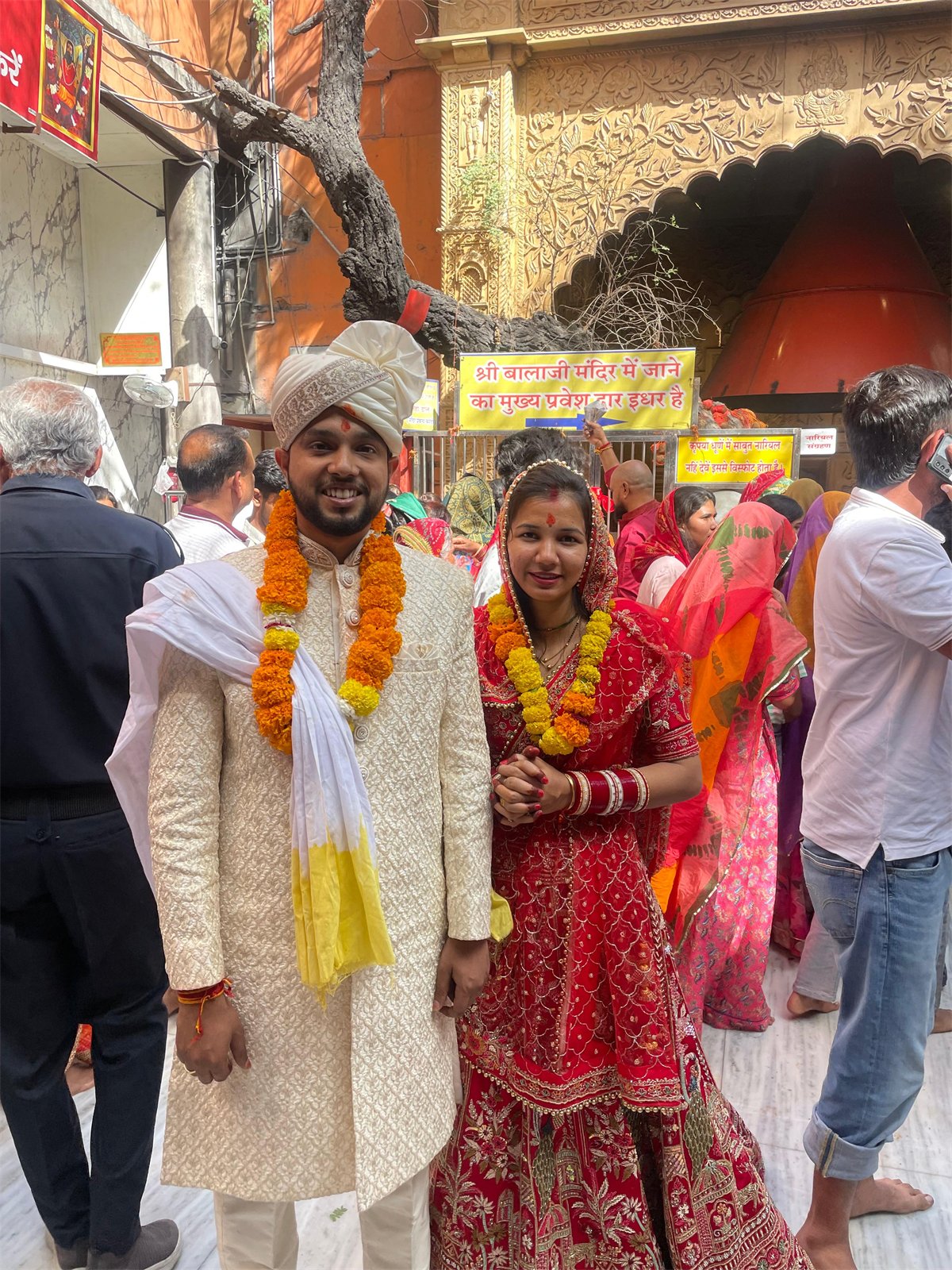 The two of us wearing wedding garlands outside a temple
