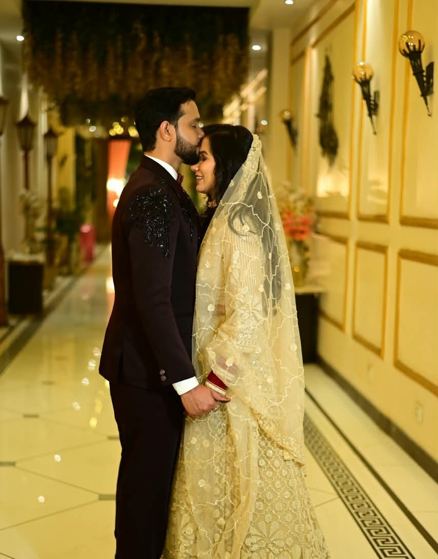 A groom kissing his bride gently on the forehead