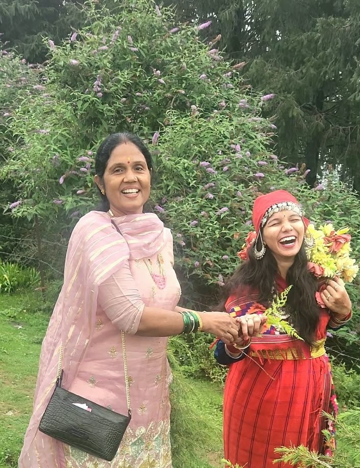 Two women laughing together outdoors with flowers